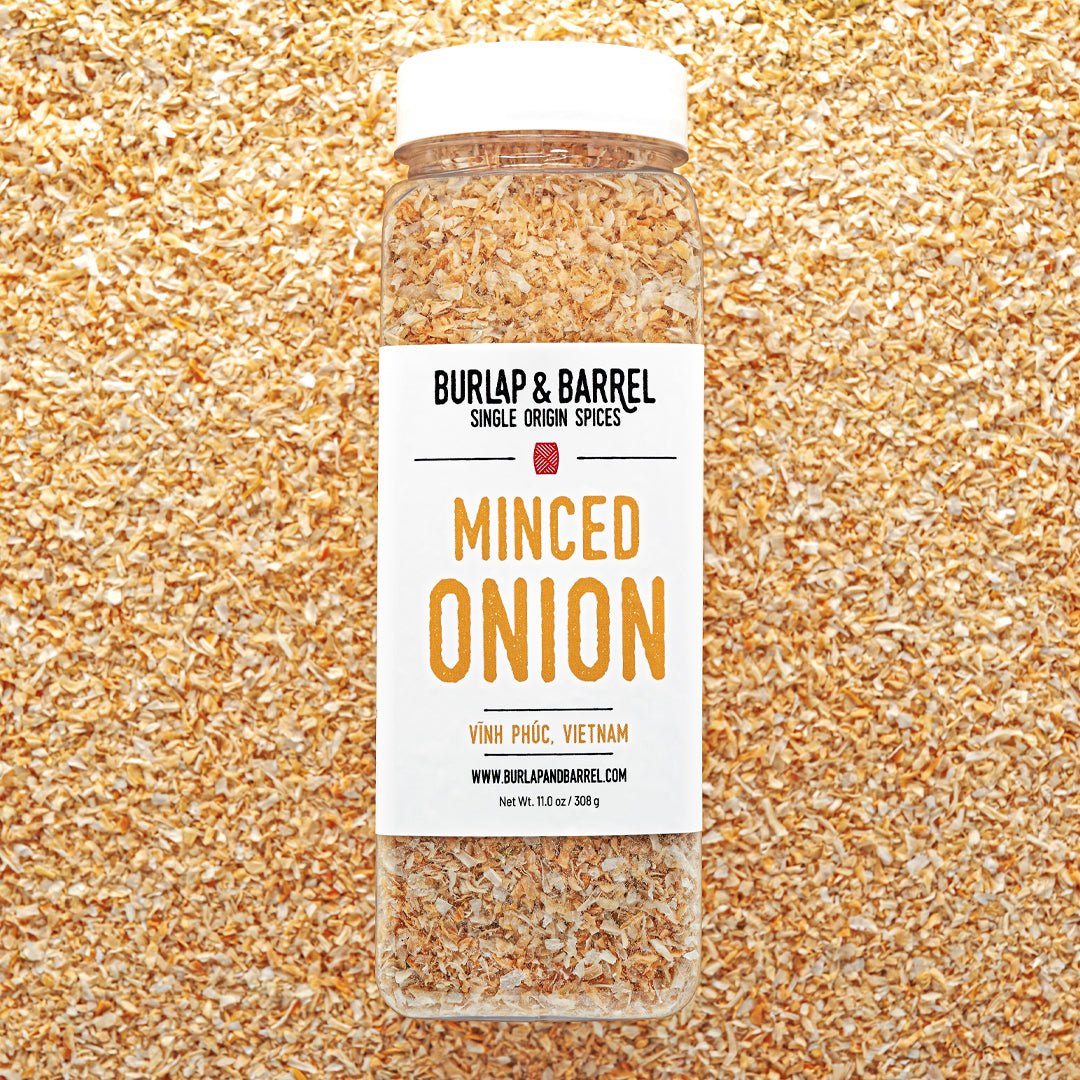 Jar of minced onion spice with Burlap & Barrel label on a textured gold background