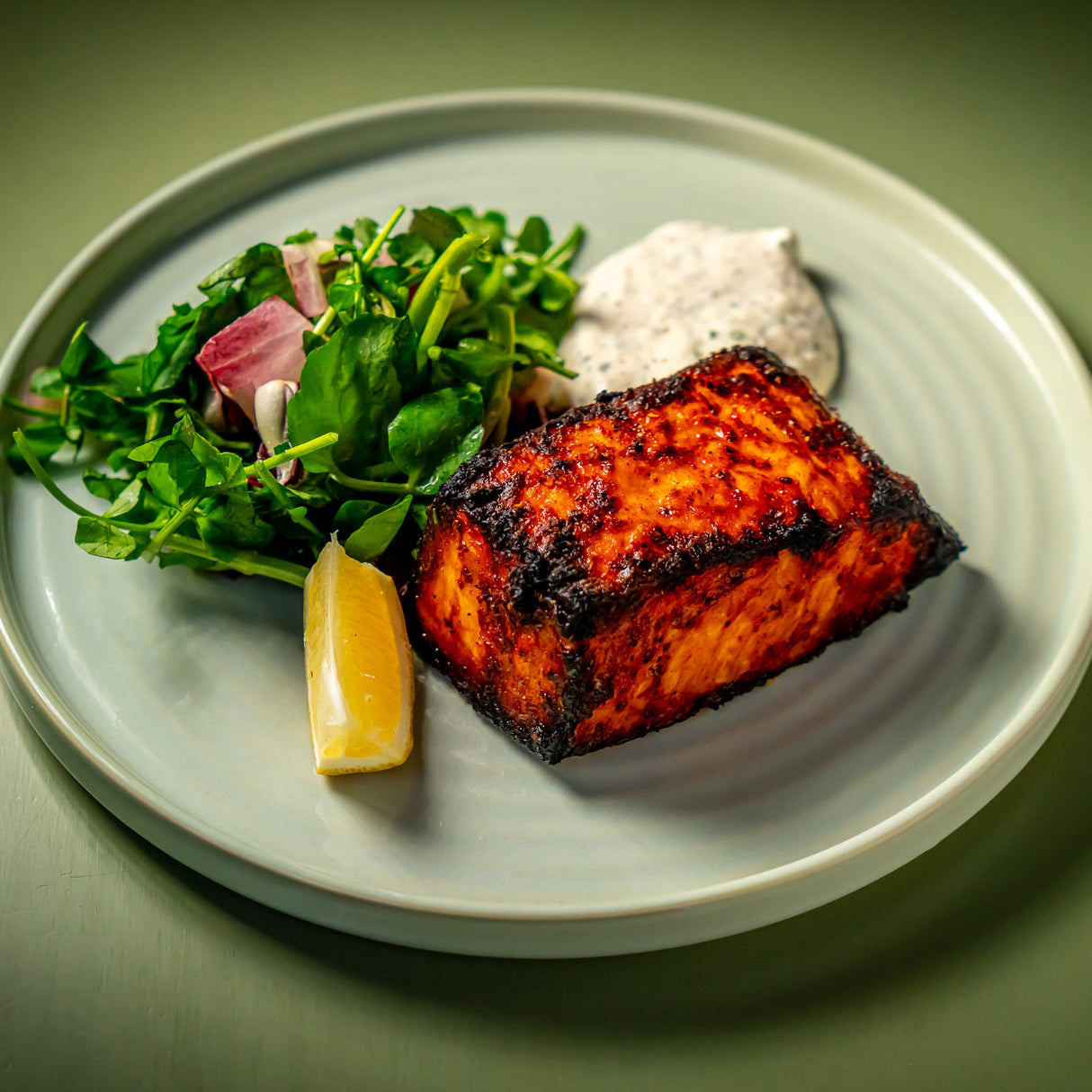 Blackened swordfish seasoned with Pardi Gras Seasfood Seasoning from Burlap & Barrel on a plate with salad, tartar sauce and a lemon wedge. Photo by Noah Feck.