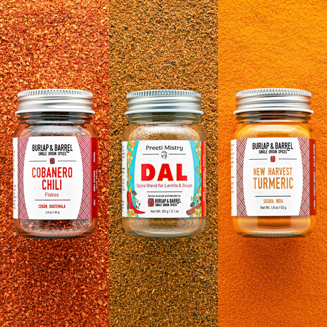 Three spice jars from Burlap & Barrel on a background of loose spices.