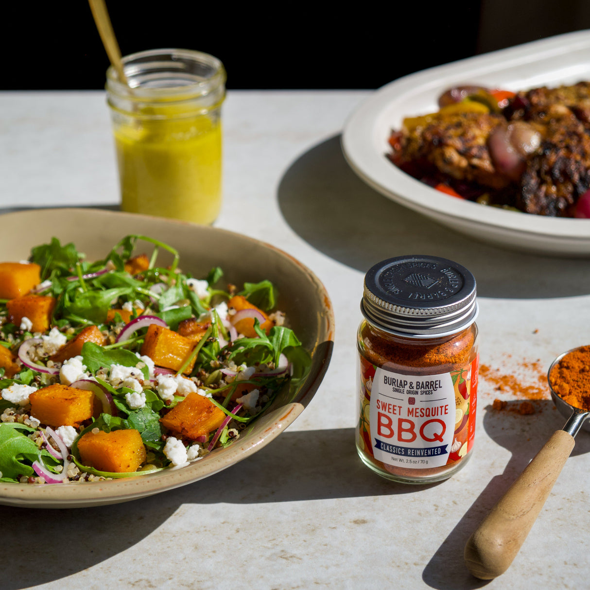 Salad with a jar of Sweet Mesquite BBQ blend from Burlap & Barrel on a table