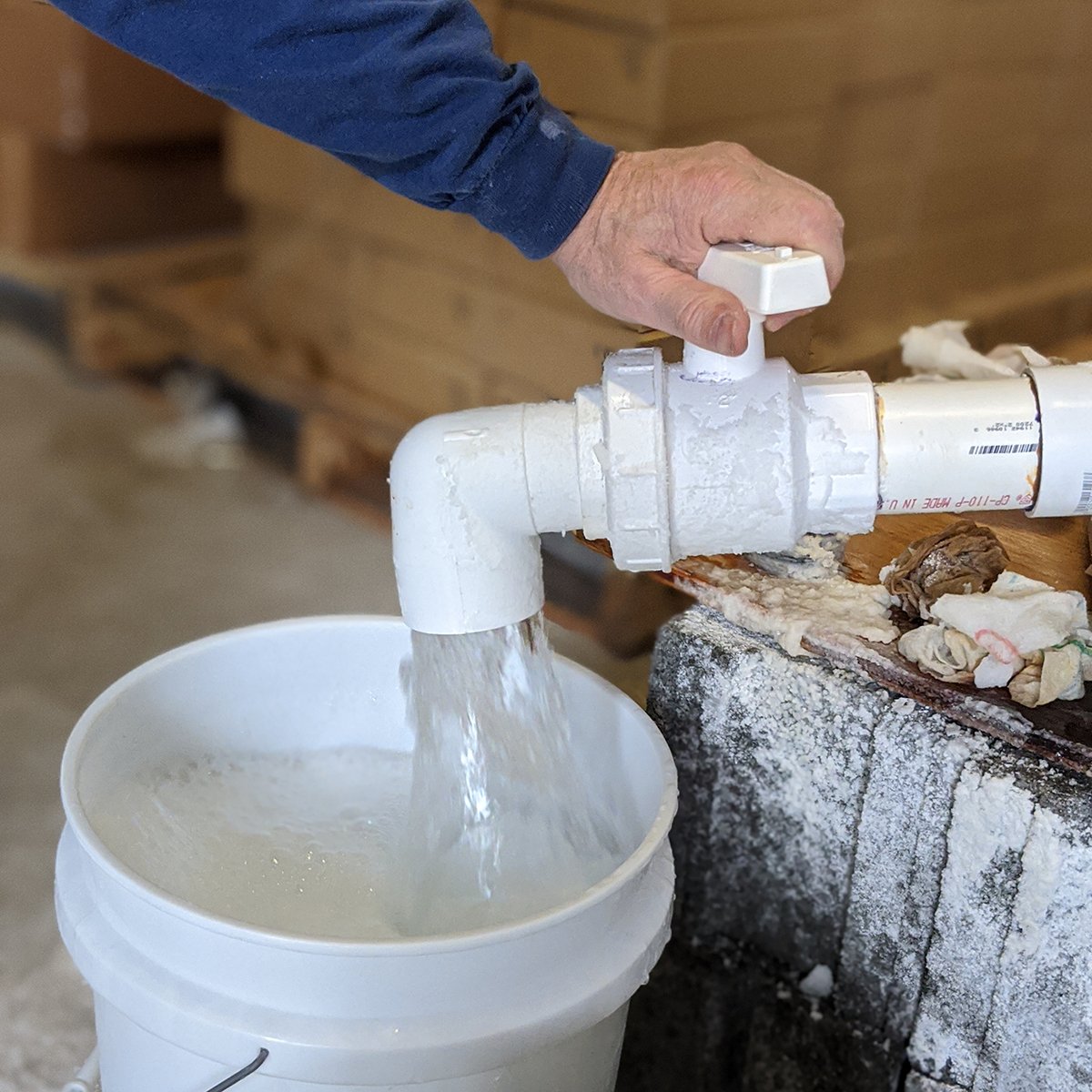 Salty water flowing from a large spigot into a white bucket.