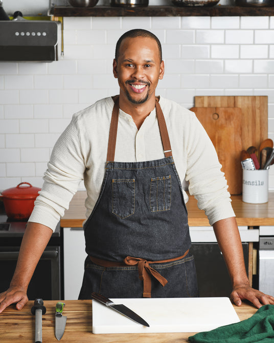 Man wearing a black apron in a kitchen setting