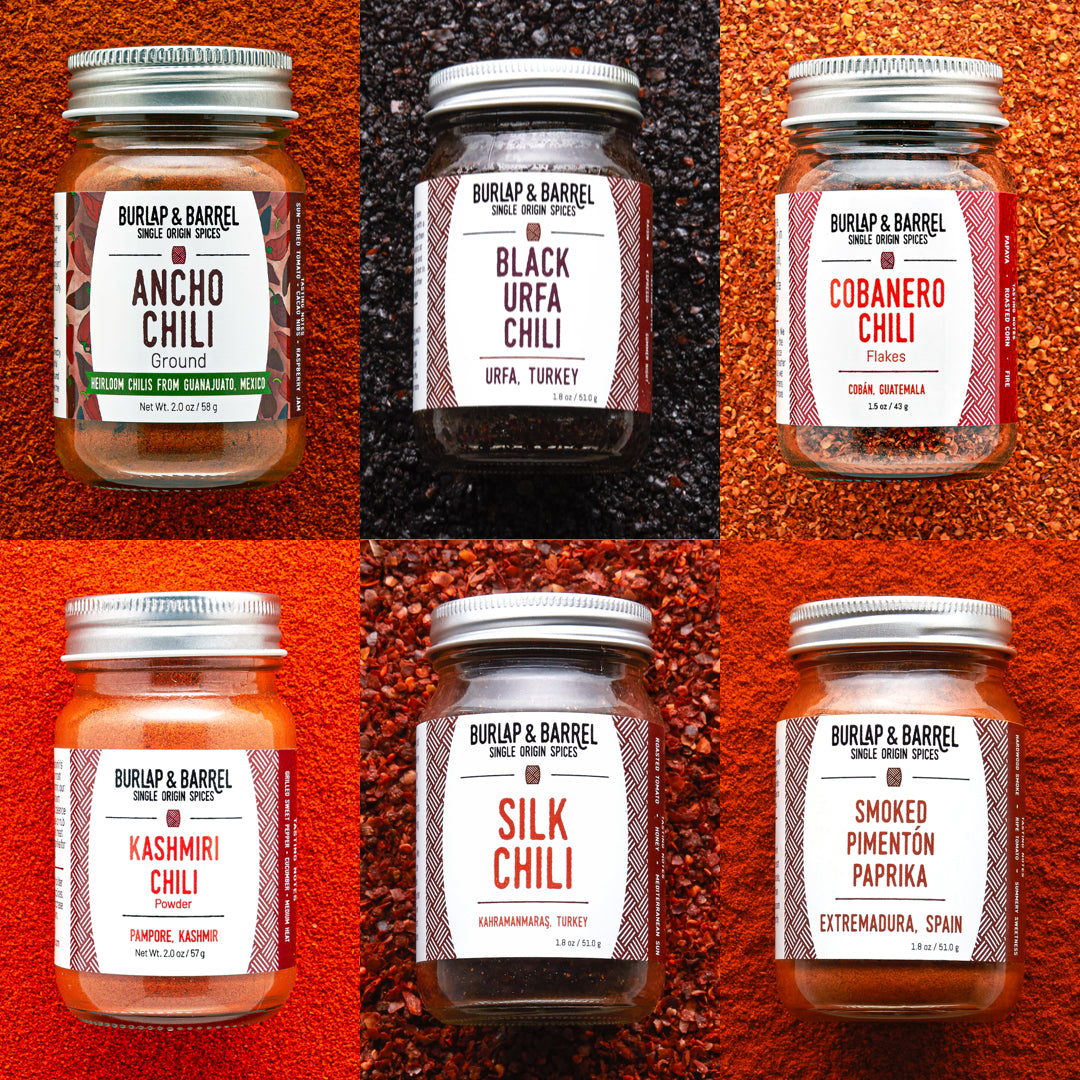 Collage of Burlap & Barrel chili spice jars with labels on a textured red background.
