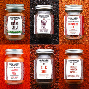 Collage of Burlap & Barrel chili spice jars with labels on a textured red background.