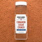 Container of BURLAP & BARREL Cinnamon Sugar Crunch spice mix on a brown textured background