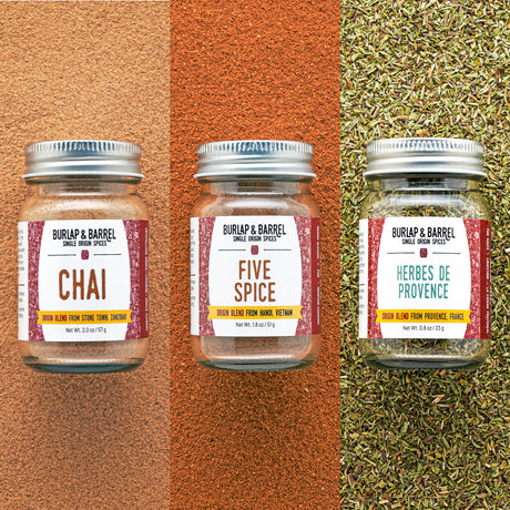 Three jars of Burlap & Barrel spices on a textured background with visible spices.