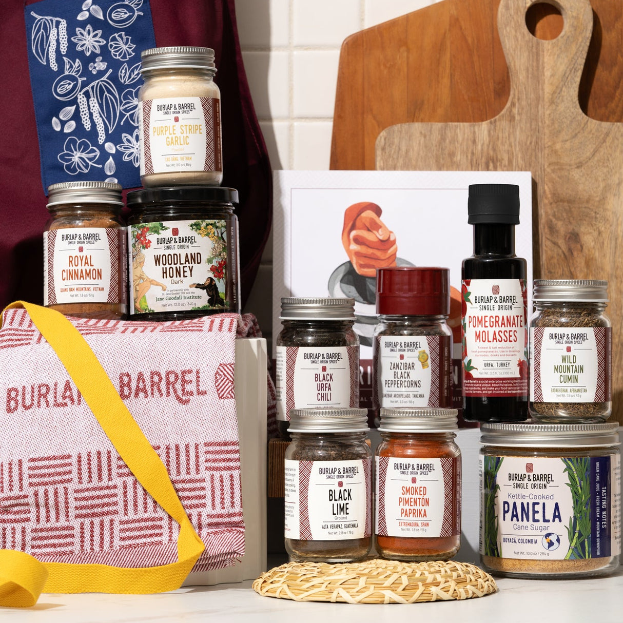 Collection of spice jars and a wooden cutting board on a kitchen counter from Burlap & Barrel