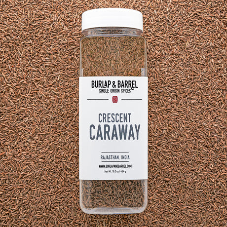 Bottle of Burlap & Barrel Crescent Caraway on a caraway seed background from Burlap & Barrel