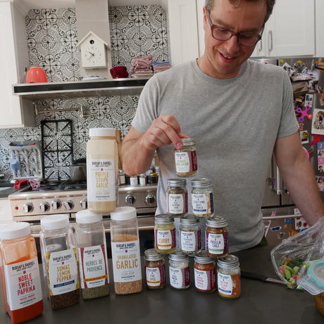 Man in a kitchen with various spice jars on the counter