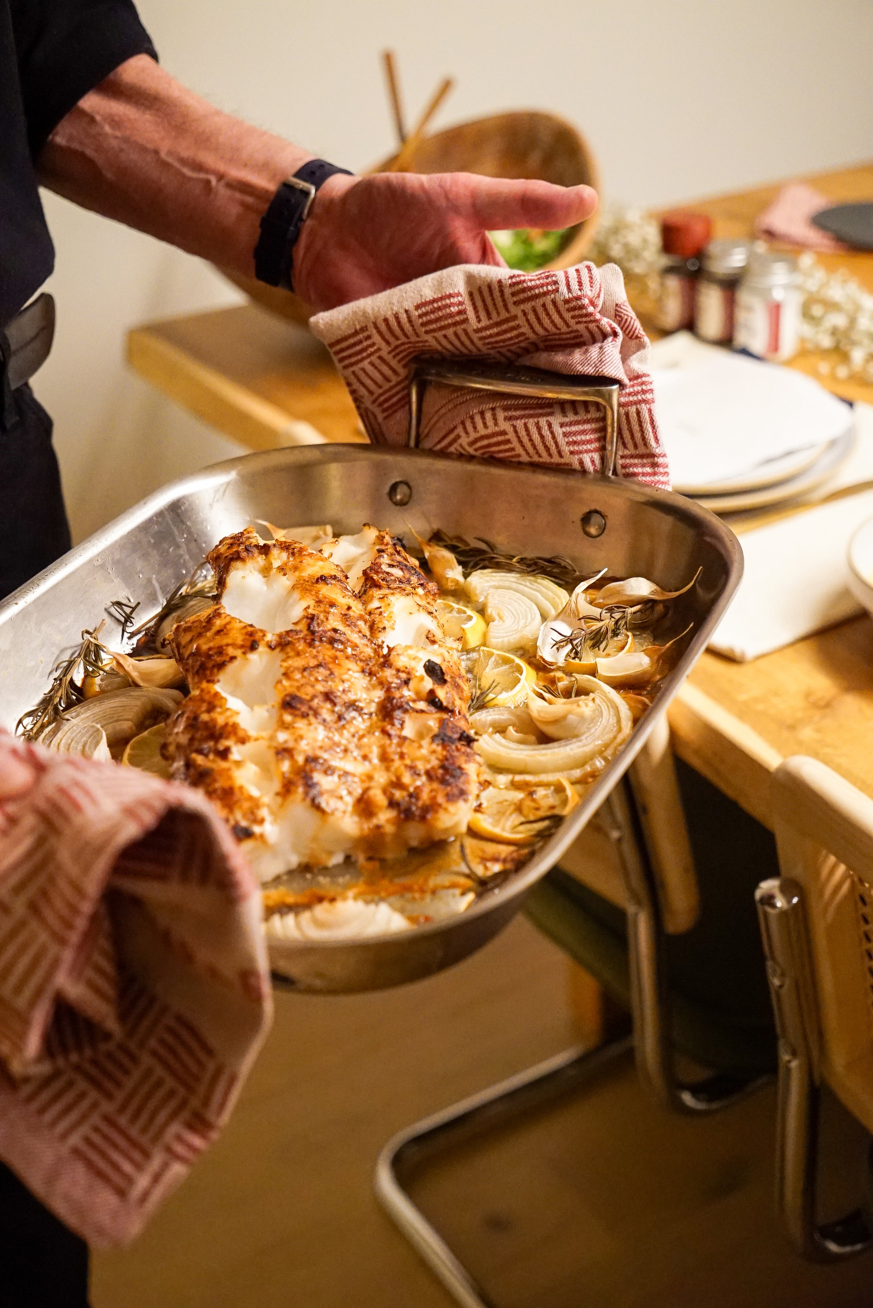 Person holding a tray with roasted fish and vegetables with Burlap & Barrel kitchen towels 