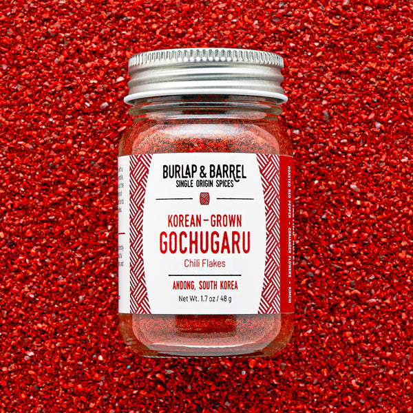 Jar of Burlap & Barrel Gochugaru chili flakes on a red background