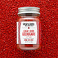 Jar of Burlap & Barrel Gochugaru chili flakes on a red background