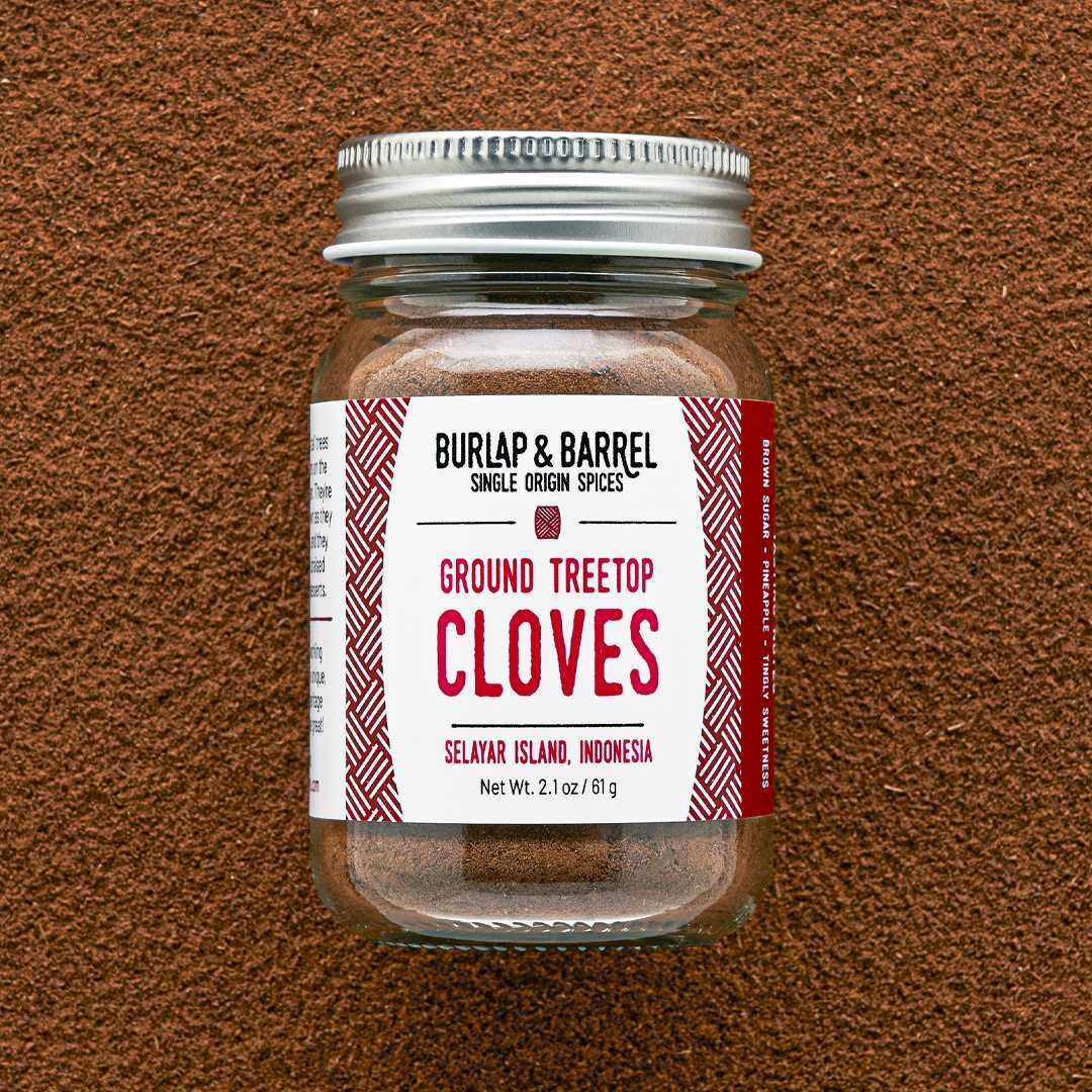 Jar of ground treetop cloves with a label on a brown textured background