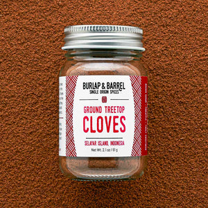Jar of ground treetop cloves with a label on a brown textured background