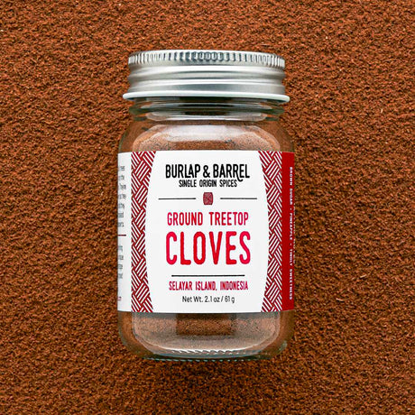 Jar of ground treetop cloves with a label on a brown textured background
