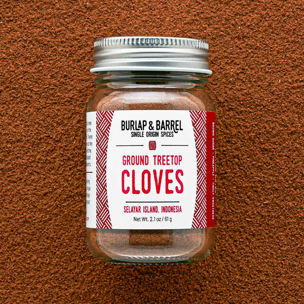 Jar of ground treetop cloves with a label on a brown textured background