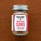 Jar of ground treetop cloves with a label on a brown textured background
