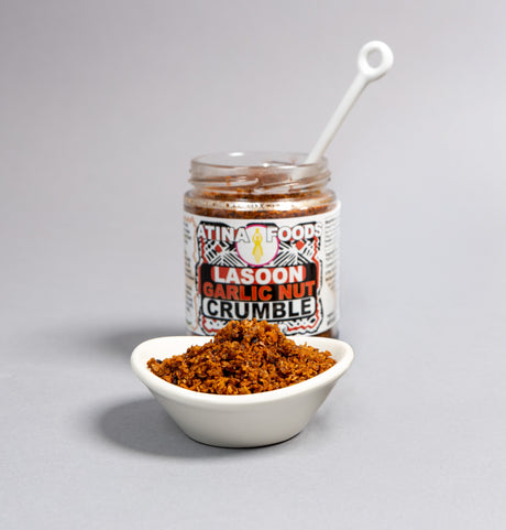 Jar of Lasoon Garlic Nut Crumble with a spoon on a gray background