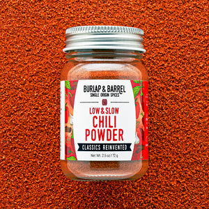 Jar of Burlap & Barrel Low & Slow Chili Powder on a textured brown background