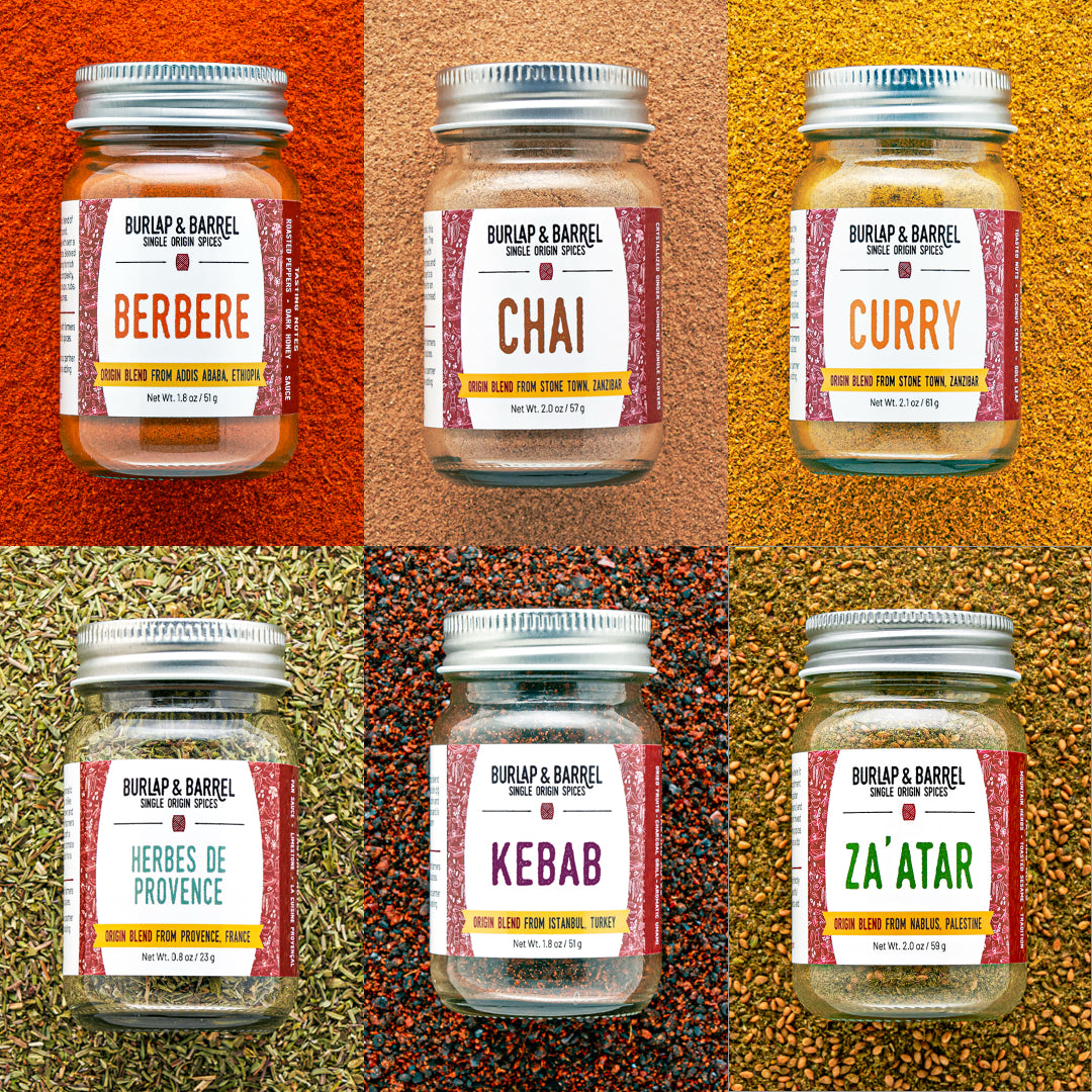 Six glass jars of Burlap & Barrel spice blends arranged in a 2x3 grid, each set against a textured background of the corresponding spice blend. The blends shown are Berbere, Chai, Curry, Herbes de Provence, Kebab, and Za'ATAR.