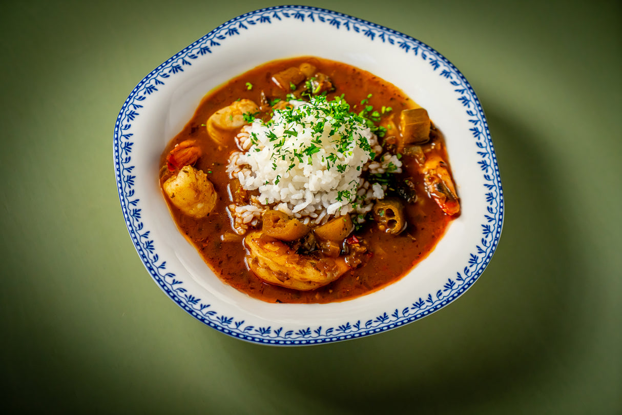  bowl of seafood stew seasoned with Pardi Gras Seafood Seasoning from Burlap & Barrel with rice on a green background. Photo by Noah Feck
