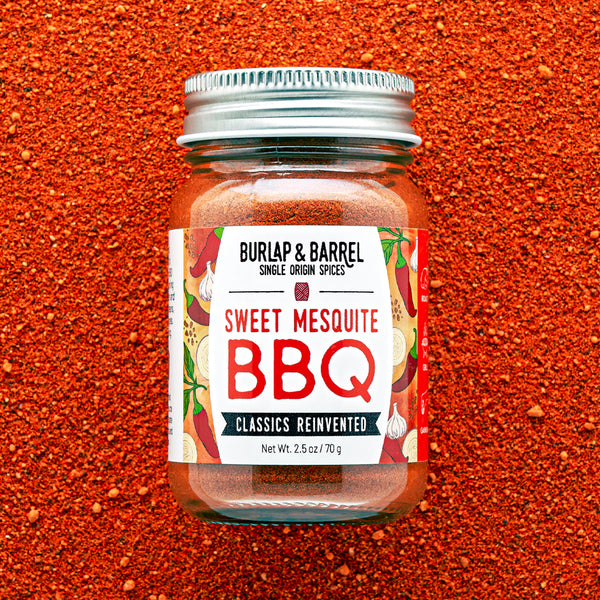 Jar of Burlap & Barrel Sweet Mesquite BBQ spice blend on a red background