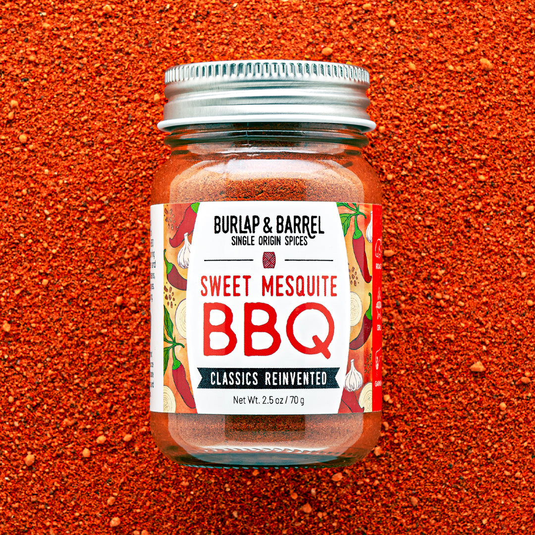 Jar of Burlap & Barrel Sweet Mesquite BBQ spice blend on a red background