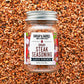 Jar of Burlap & Barrel Umami Steak Seasoning on a background of spices